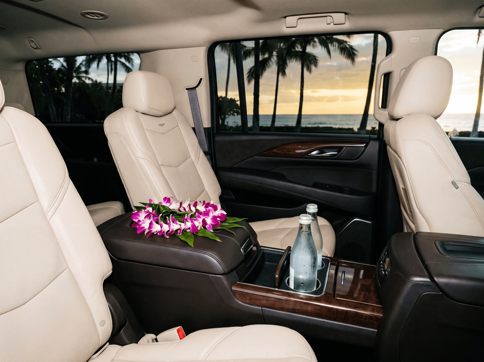 Rear cabin of a luxury SUV with a lei and water on the console
