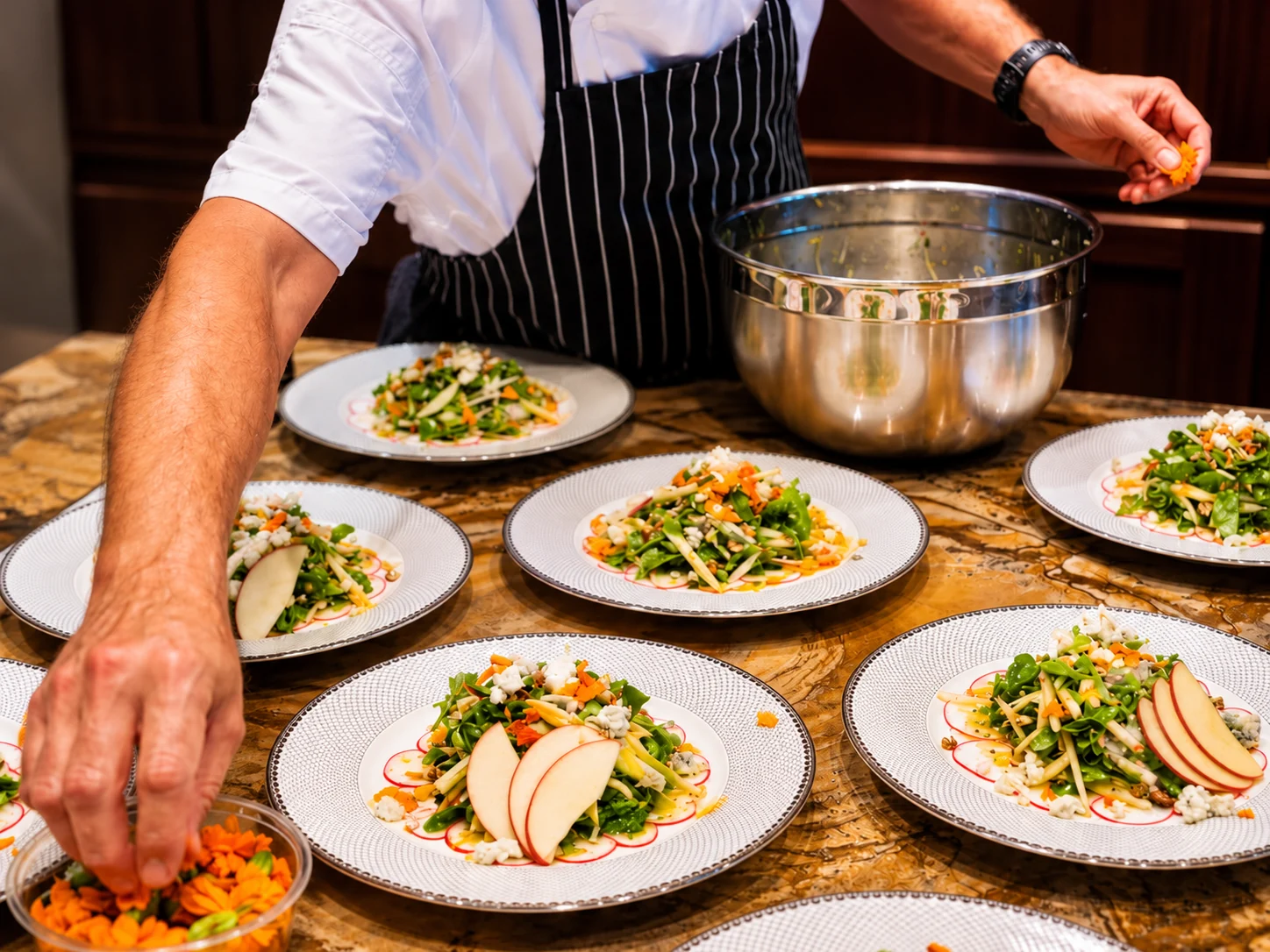 Chef’s hands finishing individually plated salads with edible flowers